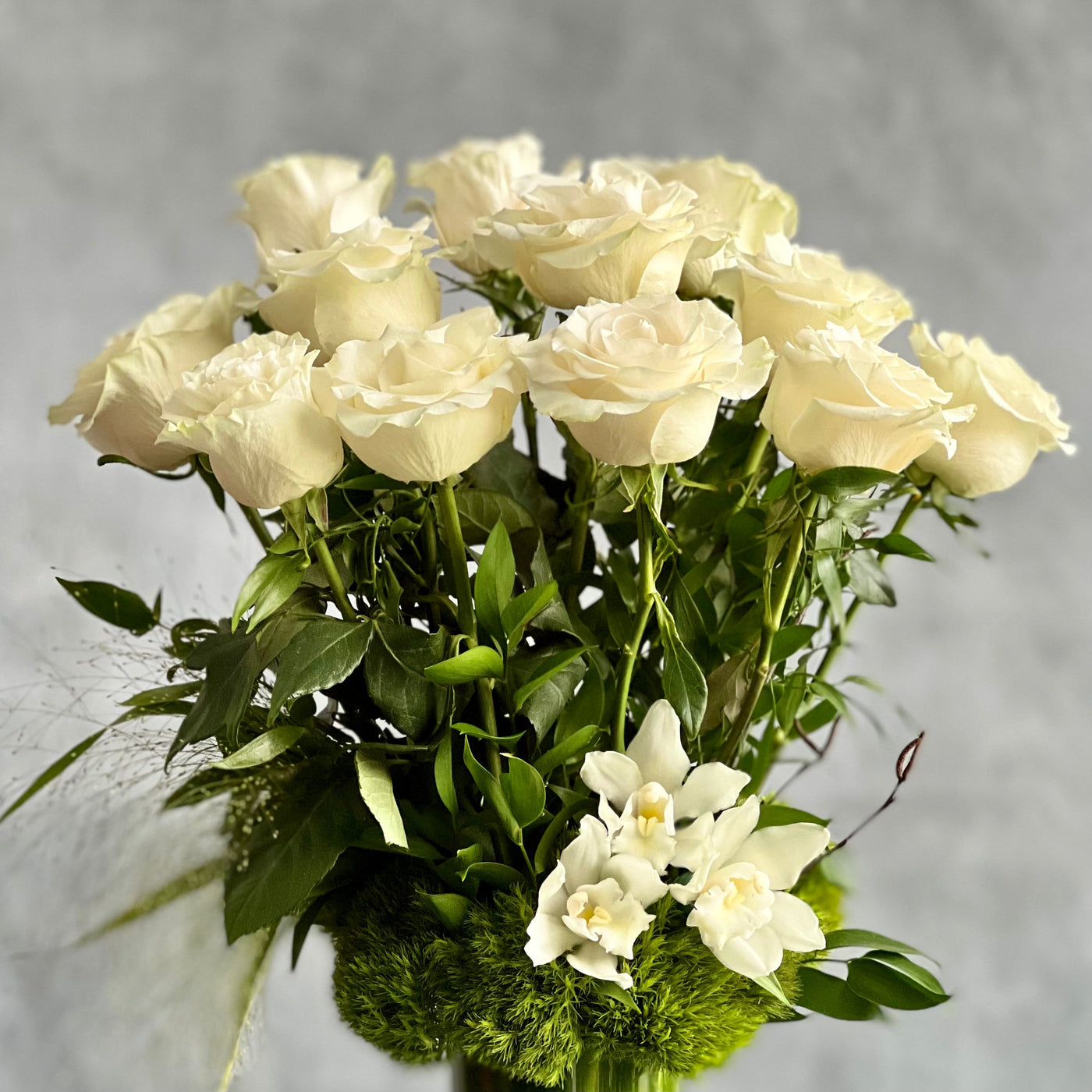 12 White Long Stem Roses Standing Tall arrangement with Ecuadorian long-stem roses and cymbidium orchids in a glass vase, available for same-day delivery by Santa Monica Florist.