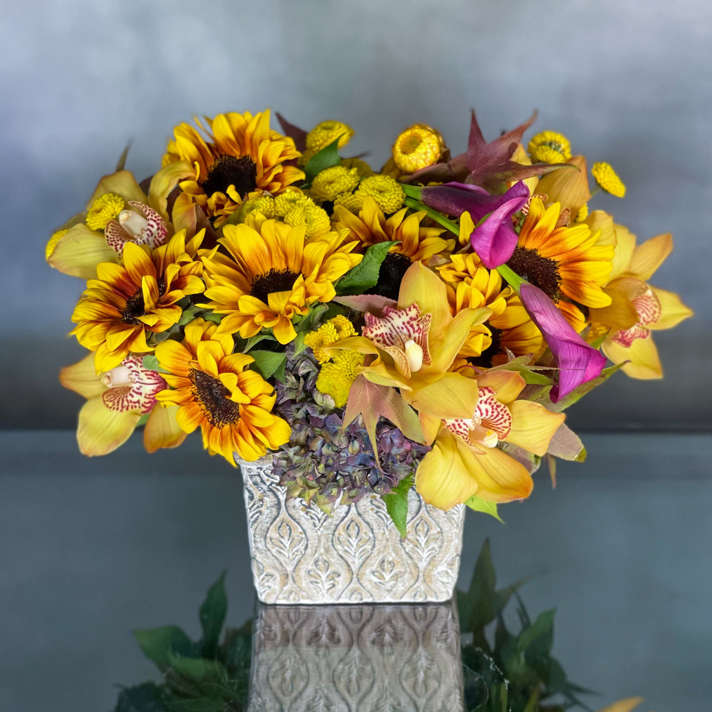 Our team presents Sunflowers hugged by antique Hydrangeas and locally grown flowers accented with imported Dutch Orchids and Call Lilies sit in a rustic 7" Square container. Santa Monica Florist presents same day delivery ! Approx. 10" Round. Beautifully arranged for Birthdays and a touch of rustic beauty for your home. Birthday, Thank you flowers, Office, Home flowers. 