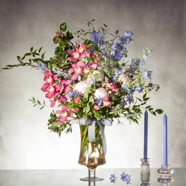A Floral Tale of Love and Beauty with pink cymbidium orchids and delphiniums in a tall glass vase, available for same-day delivery by LA Orchidia.