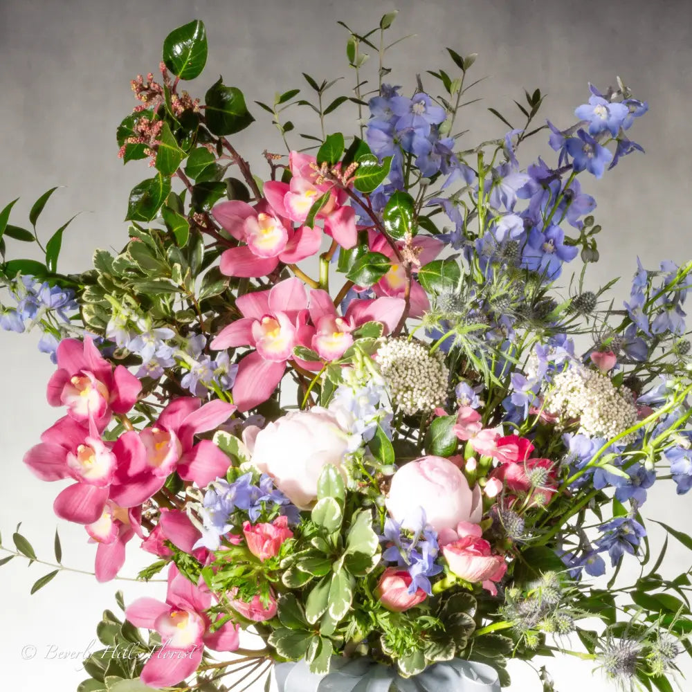 A Floral Tale of Love and Beauty with pink cymbidium orchids and delphiniums in a tall glass vase, available for same-day delivery by LA Orchidia.