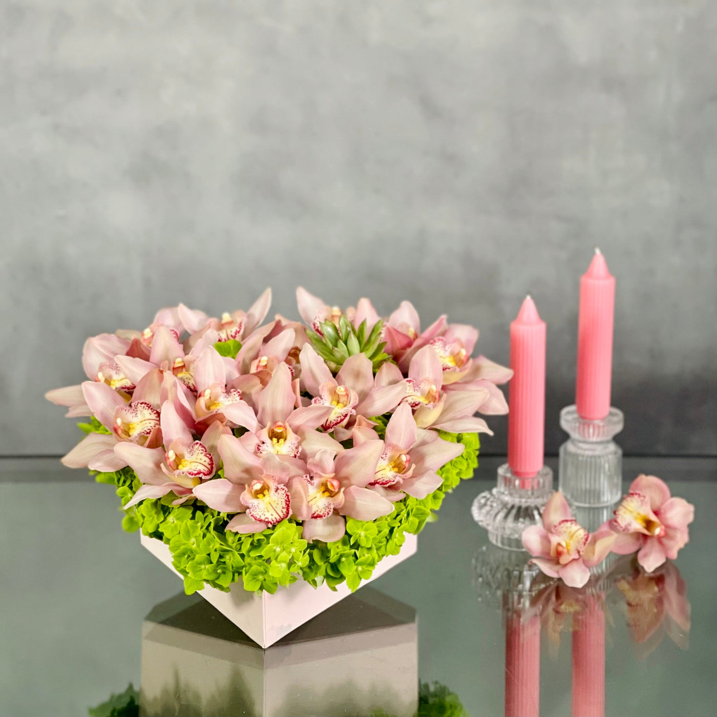 A Pink Delicate Touch arrangement with pink cymbidium orchids, hydrangeas, and succulent in a heart-shaped box, modern same-day delivery by Santa Monica Florist.