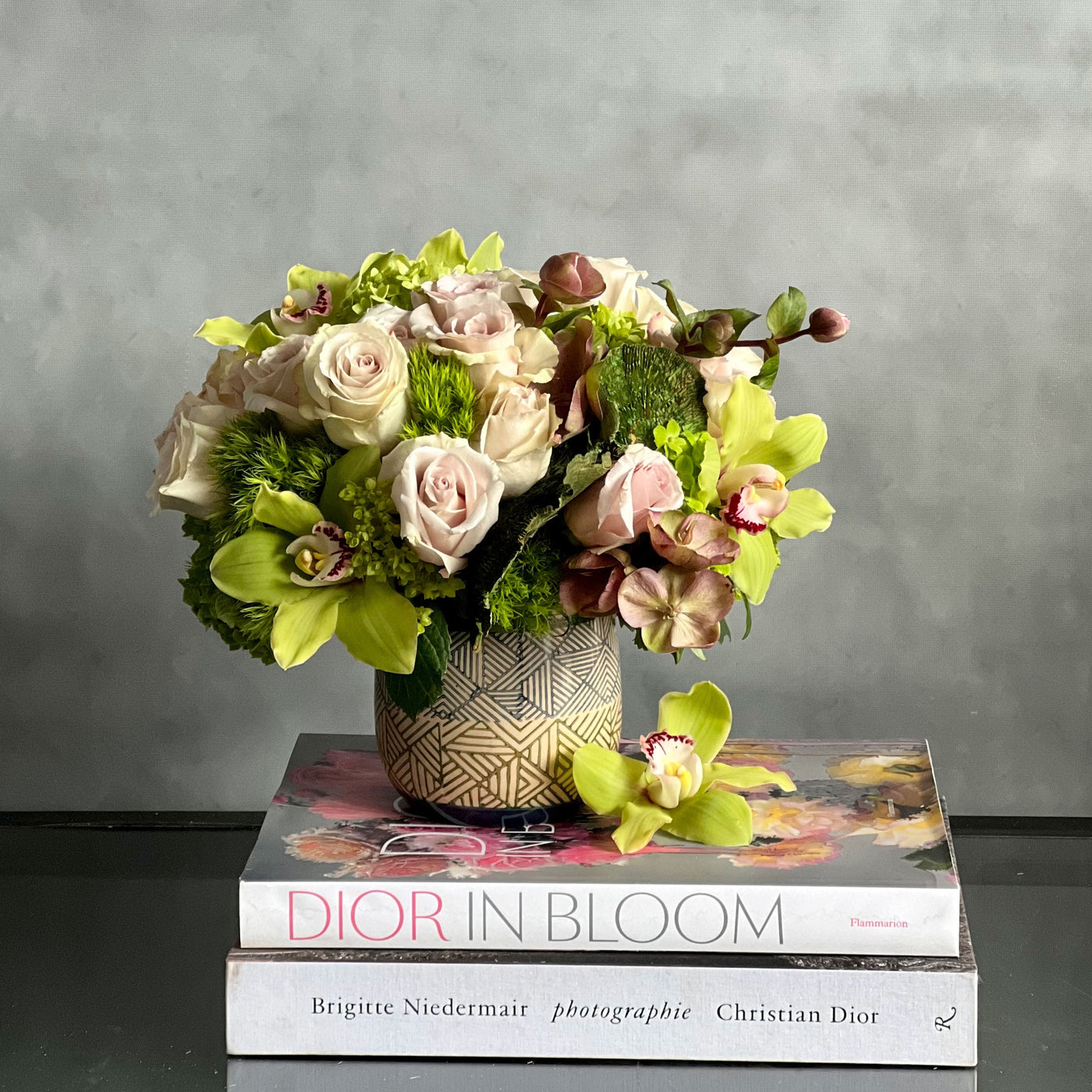 A Rustic Romance arrangement with cream roses, green cymbidium orchids, and seasonal greens in a geometric earth-toned vase, same-day delivery by Santa Monica Florist.