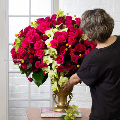 Amore Roses arrangement with red, pink, and cream roses, orchids, and spray roses in a golden pedestal container, available for same-day delivery by Santa Monica Florist.