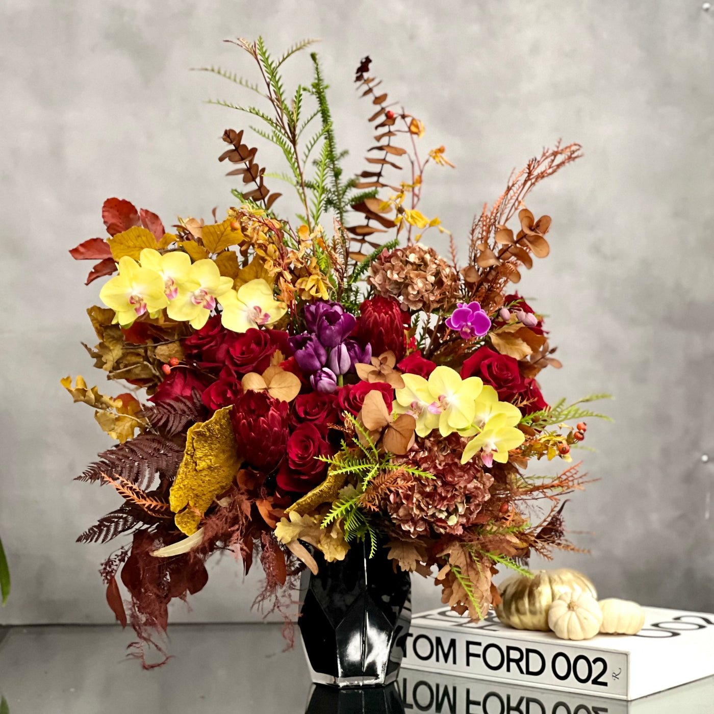 Autumn Harmony arrangement with fall flowers in vibrant reds, oranges, yellows, and browns, set in a black geometric vase, available for same-day delivery by Santa Monica Florist.