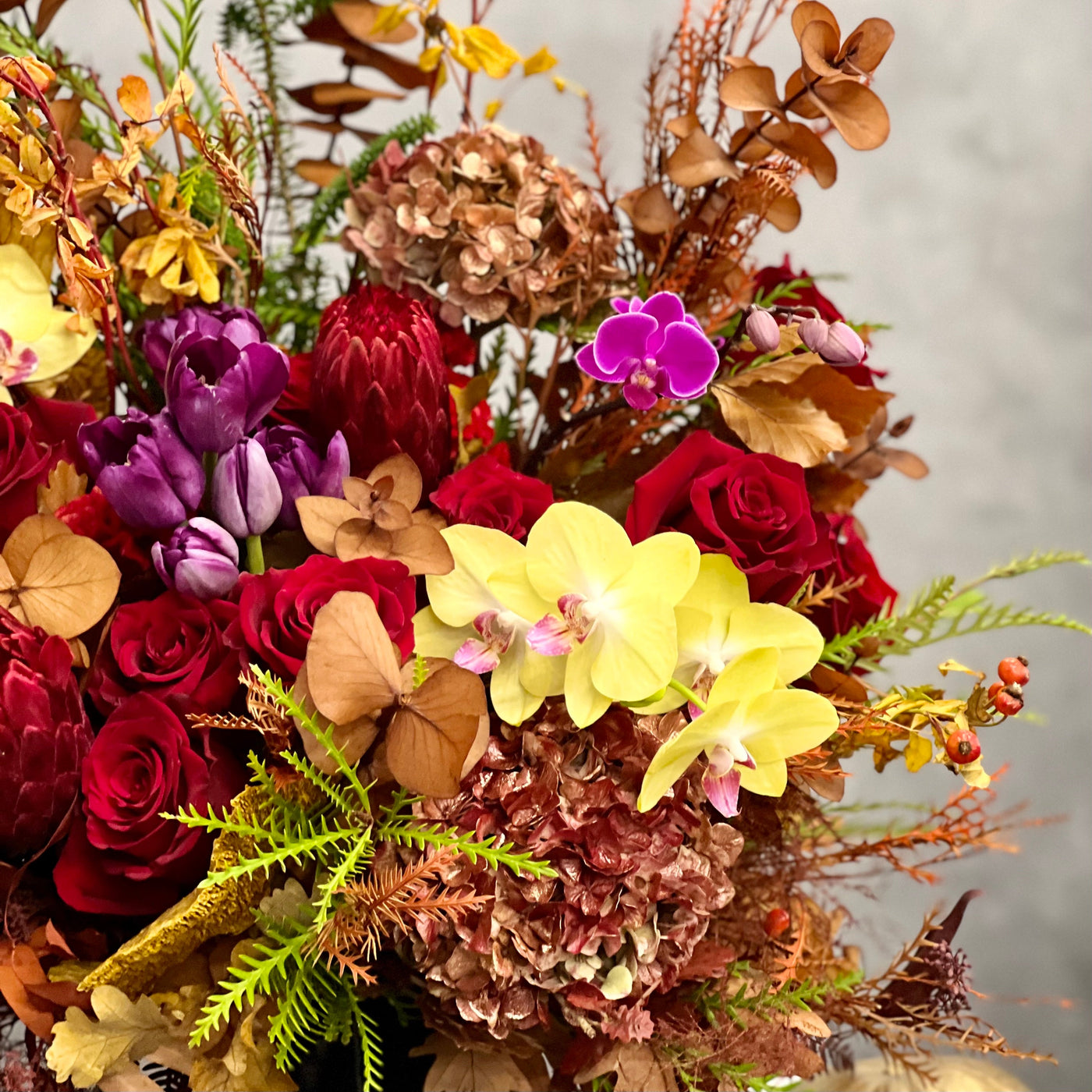 Autumn Harmony arrangement with fall flowers in vibrant reds, oranges, yellows, and browns, set in a black geometric vase, available for same-day delivery by Santa Monica Florist.