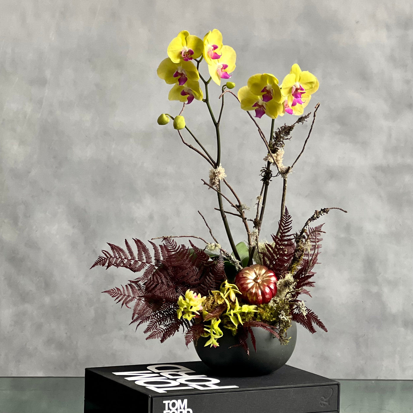 Beautiful as Always double yellow orchids with fall accents in a modern matte black ceramic bowl, available for same-day delivery by Santa Monica Florist.