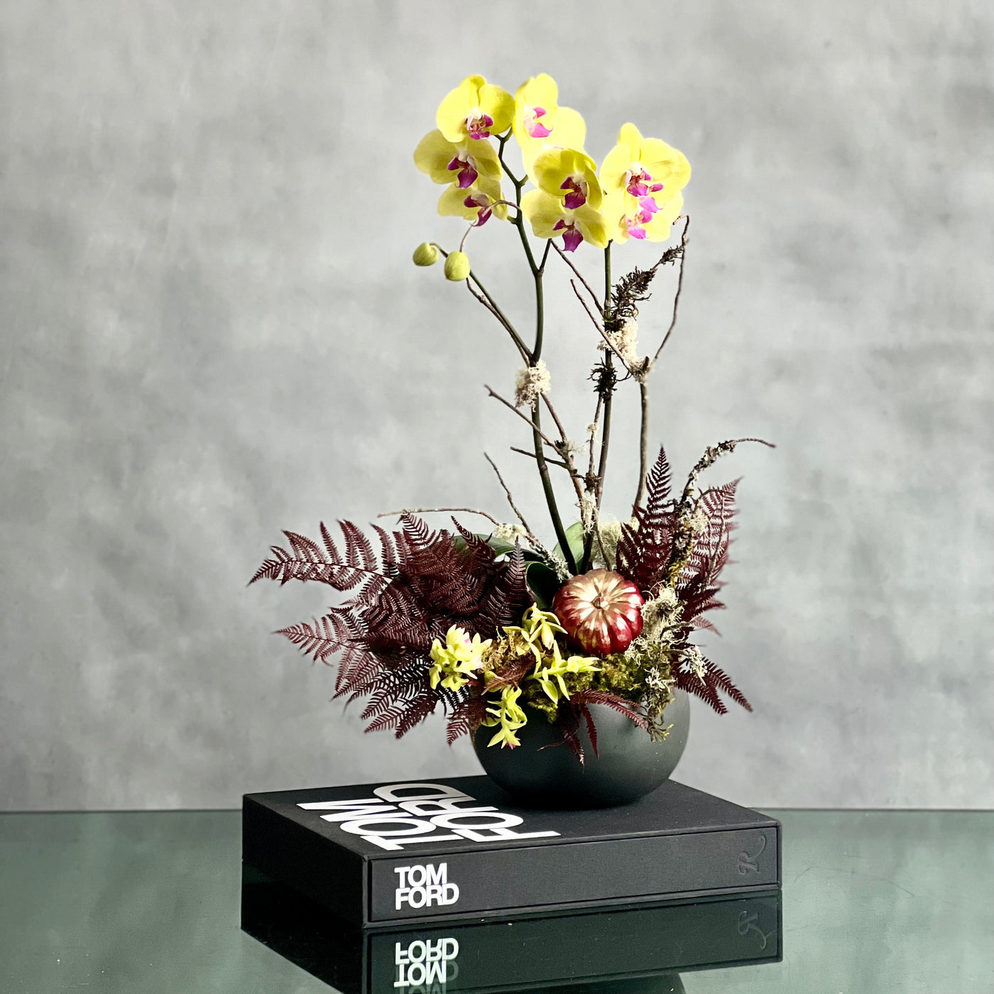 Beautiful as Always double yellow orchids with fall accents in a modern matte black ceramic bowl, available for same-day delivery by Santa Monica Florist.