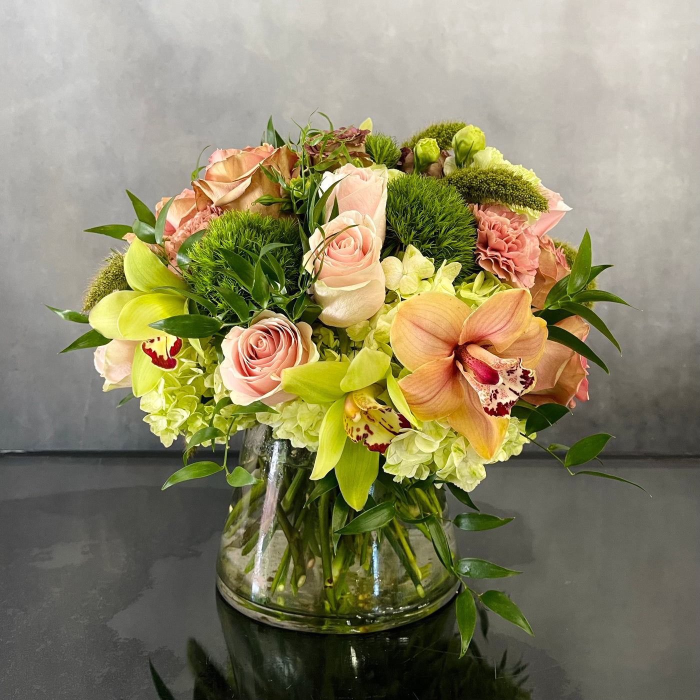 Beautiful Garden arrangement with pink roses, green and peach orchids, hydrangeas, and dianthus in a 6x6 cylinder vase, available for same-day delivery by Santa Monica Florist.