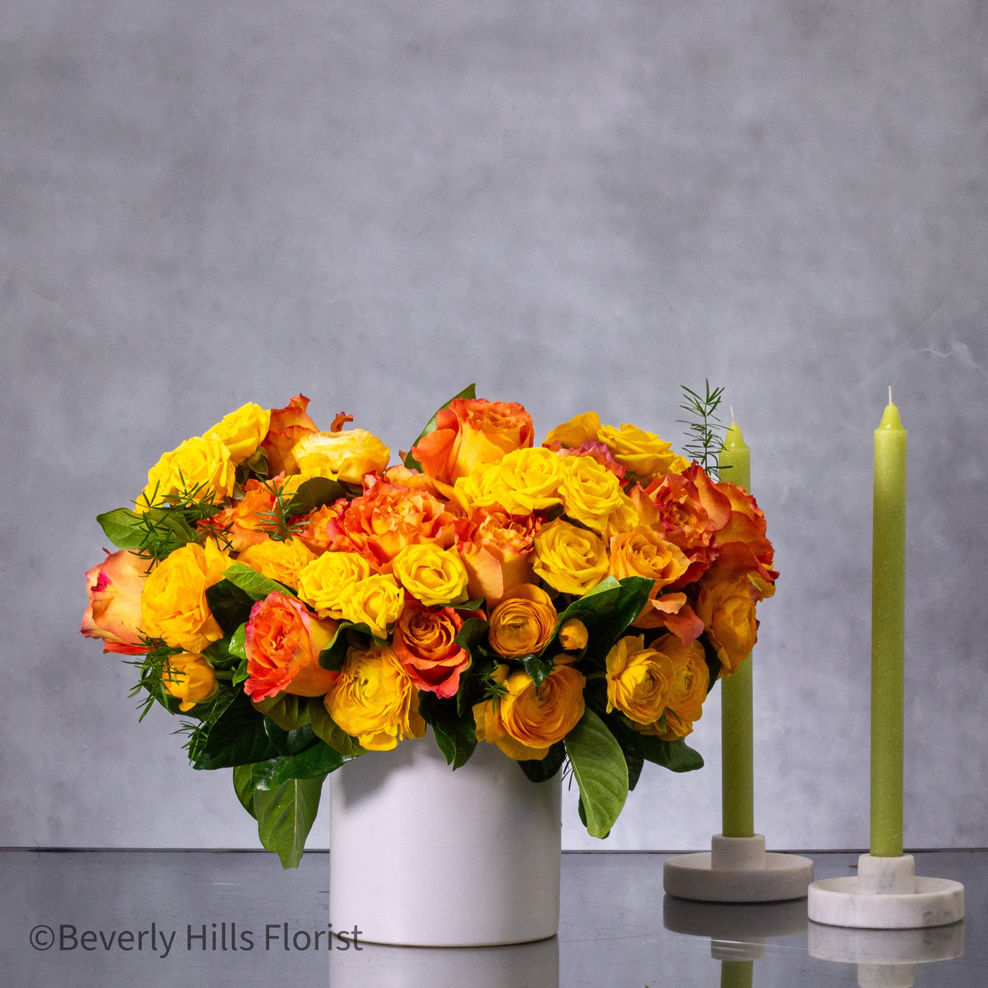 Compact floral arrangement with orange peel-colored blooms in a white ceramic vase, perfect for same-day delivery.