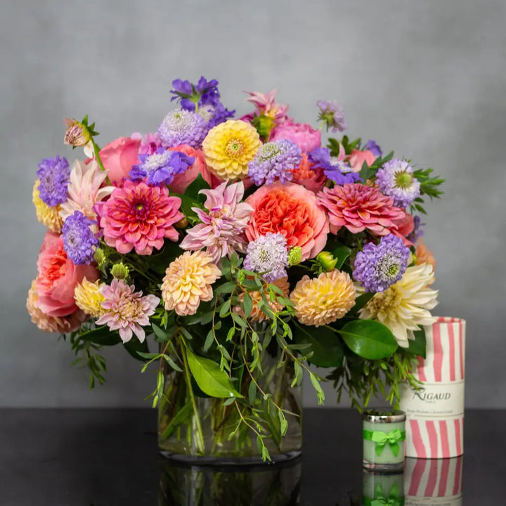 Colorful garden-style flower arrangement with dahlias, peonies, and roses in a glass vase