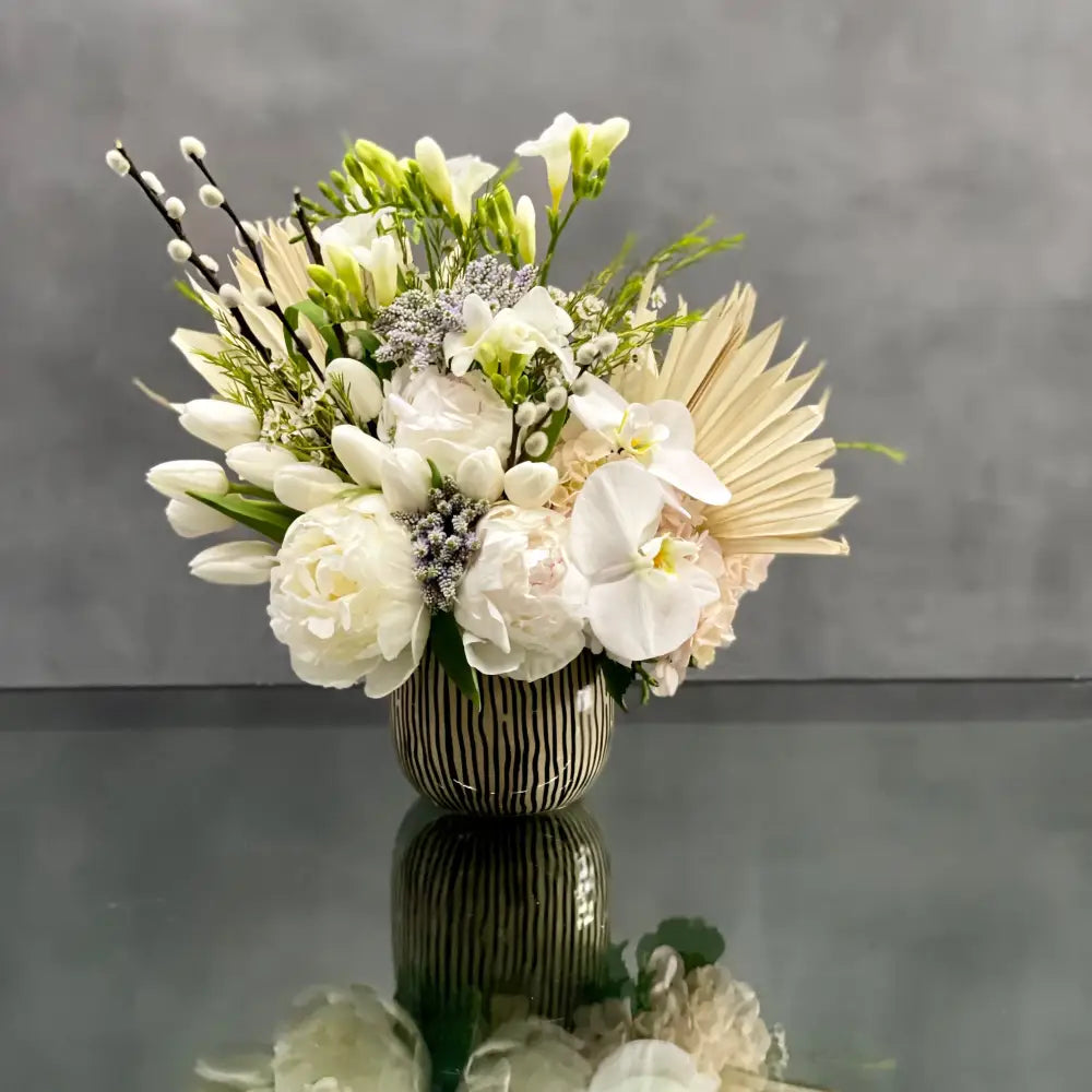 This arrangement is made with a designer's choice array of seasonal white flowers. Floral could include Roses, Hydrangeas, Orchids, Tulips and or Peonies. These beautiful white flowers are an excellent choice for weddings, funerals and other major life events. Our team at LA Orchidia offers same day delivery! 