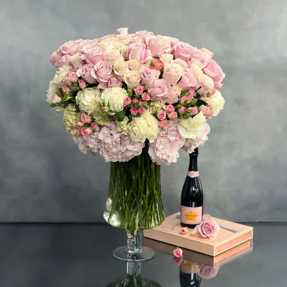 Elegant arrangement of over 100 pale pink roses and peonies in a sleek glass vase, 28 inches tall, designed by Santa Monica Florist.