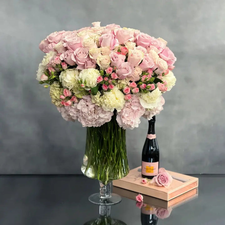 Elegant arrangement of over 100 pale pink roses and peonies in a sleek glass vase, 28 inches tall, designed by Santa Monica Florist.