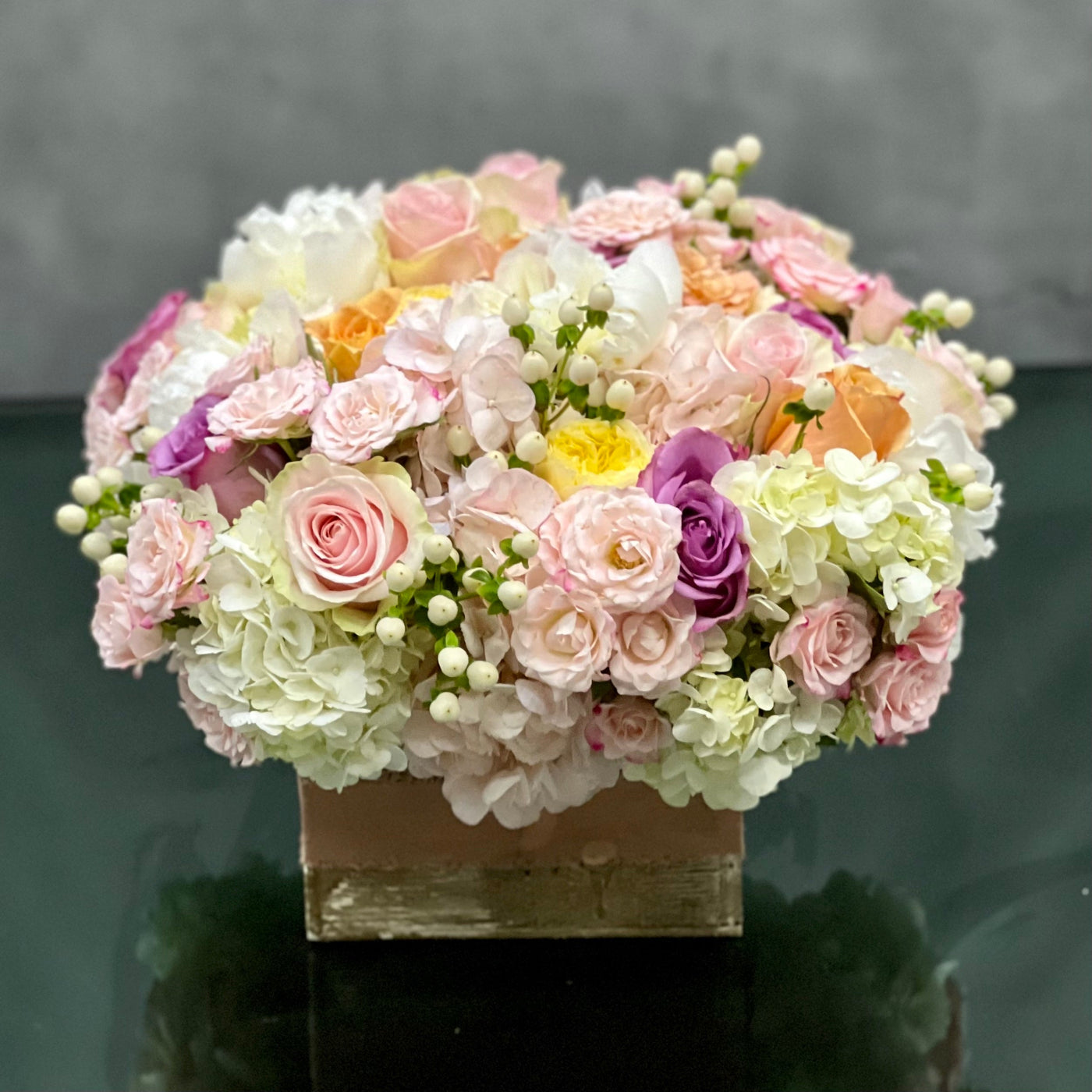 Pastel Perfection floral arrangement with soft pastel roses, Dutch hydrangeas, and seasonal flowers in a box base tied with a cream bow, available for same-day delivery.