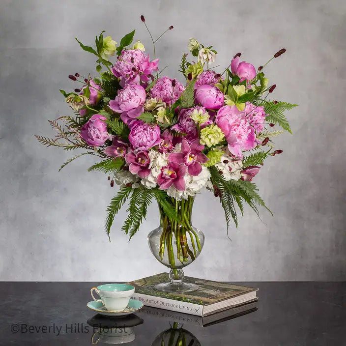 Elegant Floral Fusion arrangement with peonies, cymbidium orchids, and white hydrangeas in a tall glass vase.