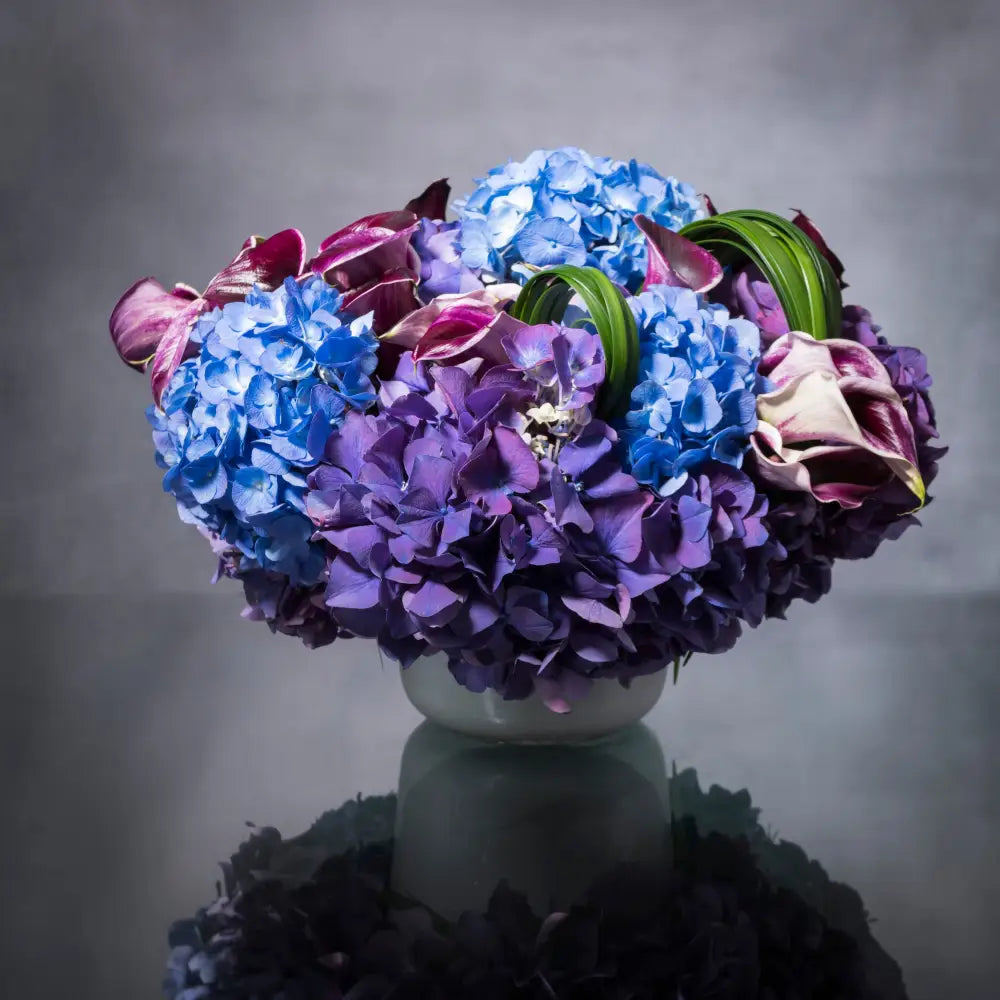 Our team at LA Orchidia offers same day delivery ! This arrangement of purple and blue Hydrangeas with deep purple calla lilies in a frosted glass vase. The deep and regal colors of this large arrangement are sure to leave an impression as a gift for any occasion. Thank you flowers, Birthday flowers, flowers for him, just because flowers, home flowers
