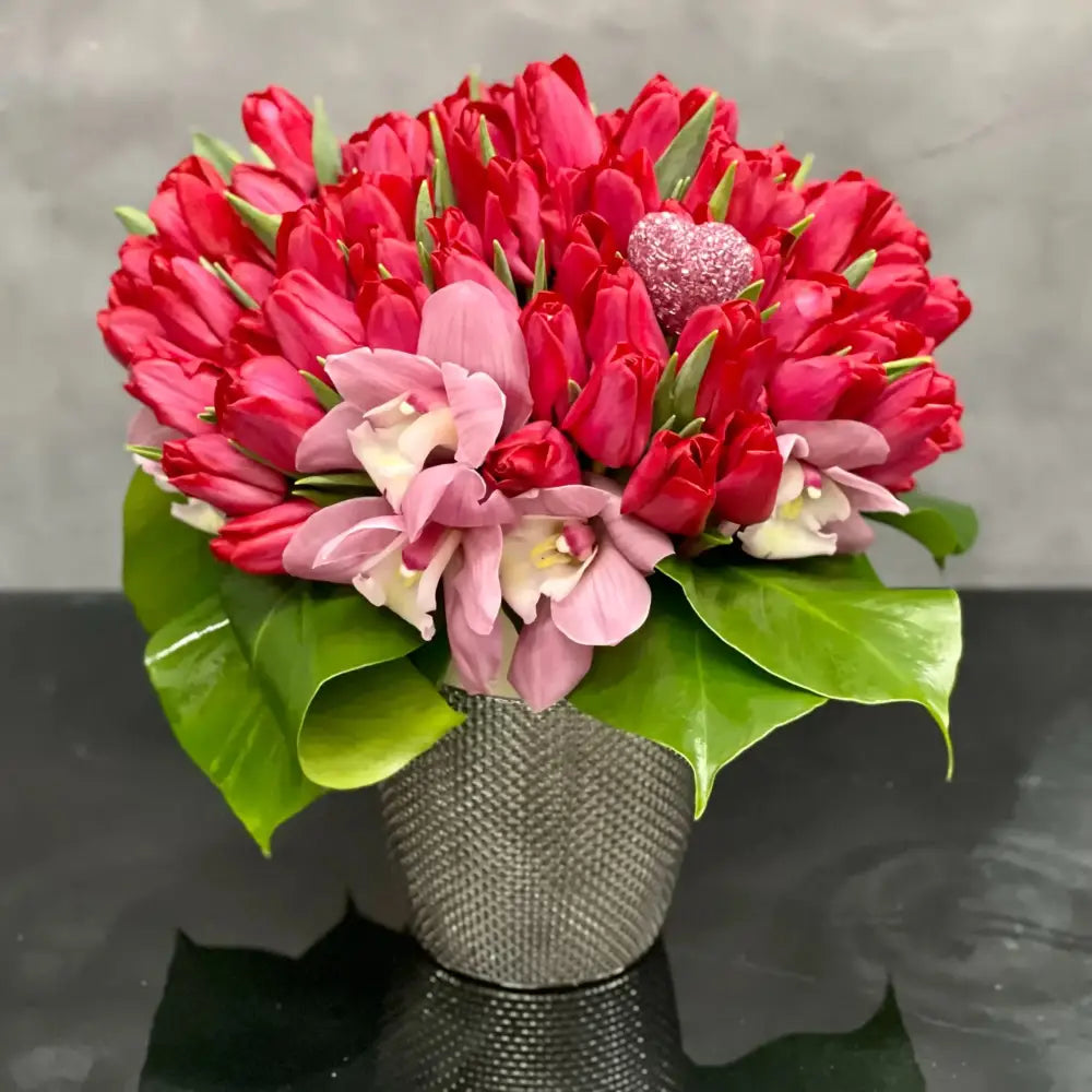 50 Beautiful dress-up pink Tulips from LA Orchidia that stand tall and are available for same day delivery! Placed in beautiful modern silver vase. Orchids and greens at its base add to the beauty and delight of this sweet design. A chic and contemporary look that's a great choice for many occasions. This arrangement becomes approximately  10" W x 16" H. Birthday flowers, thank you flowers, get well flowers, congratulations flowers