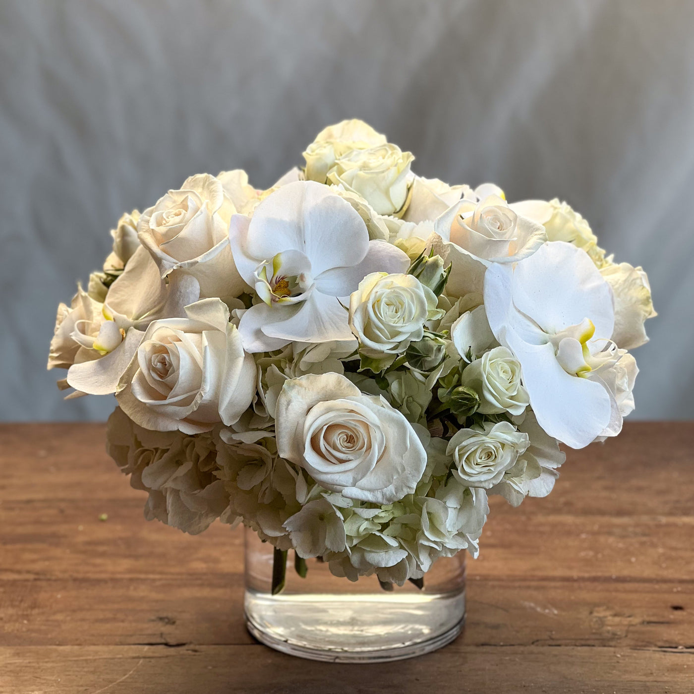 Elegant white roses and orchids arrangement in a glass vase, Santa Monica Florist.