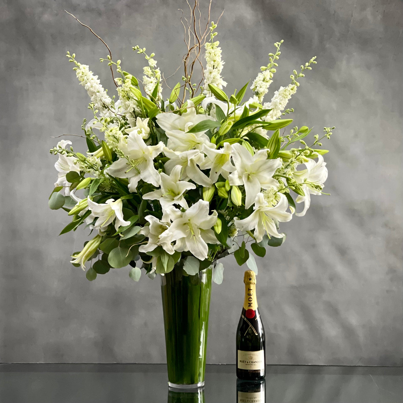 This Display of over 20 Stems of Crystal White Lily's accented with locally Grown Flowers and Greens is available for same day Delivery at Santa Monica Florist. This Bouquet is placed in a leaf lined 14" Tall vase with an opening of 5" and it is Approx. 45" Tall and 32 Wide. Birthday Flowers, Just because flowers, thinking of you flowers