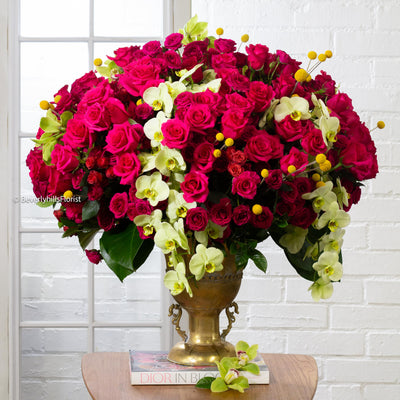 Amore Roses arrangement with red, pink, and cream roses, orchids, and spray roses in a golden pedestal container, available for same-day delivery by Santa Monica Florist.